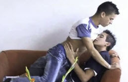 Dos jóvenes latinos besándose y desnudándose en el sofa